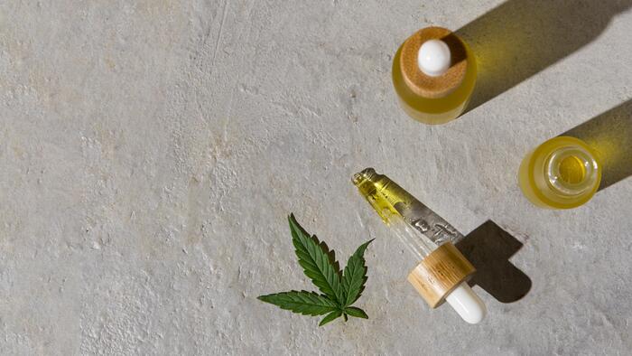 Óleo de Cannabis em um frasco de vidro ao lado de conta-gotas e folha da planta maconha
