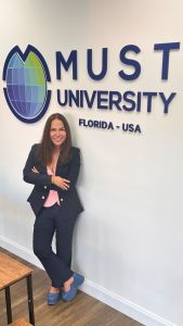 Sandra Teschner em frente a letreiro da MUST University, Flórida - EUA