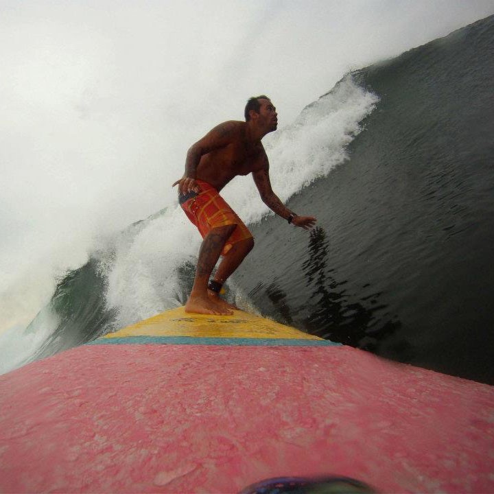 Foto de Washington de pé sobre uma prancha de surf pegando uma onda