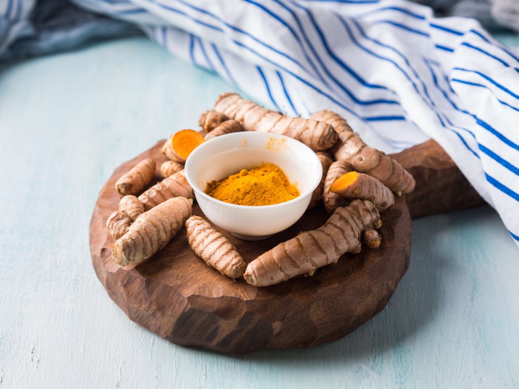 Açafrão-da-terra em pó e em raízes sobre uma mesa