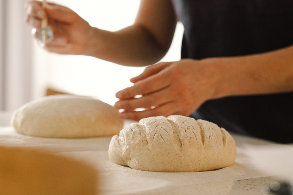 Mãos de mulher preparando massa de pão para assar